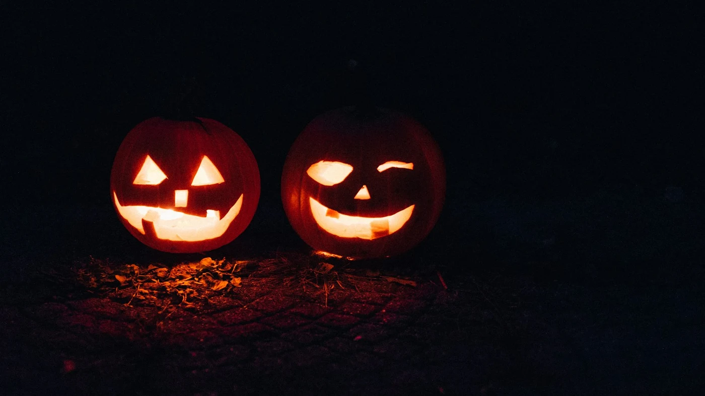 Two hand-carved jack-o’-lanterns glowing at night